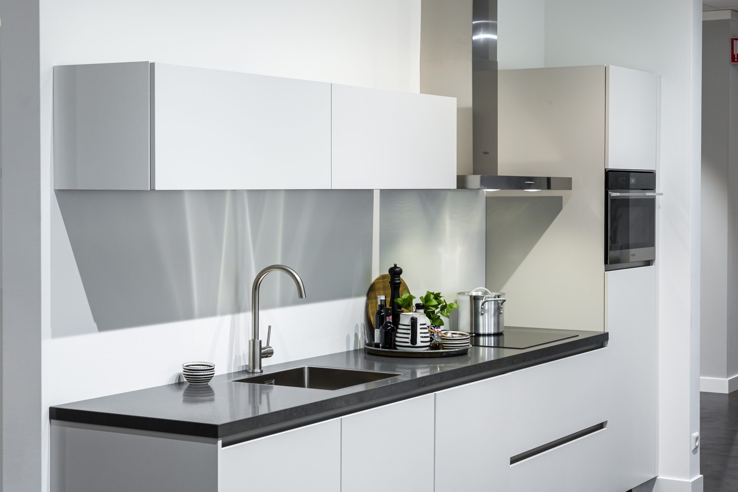 Witte greeploze rechte keuken met donker keukenblad