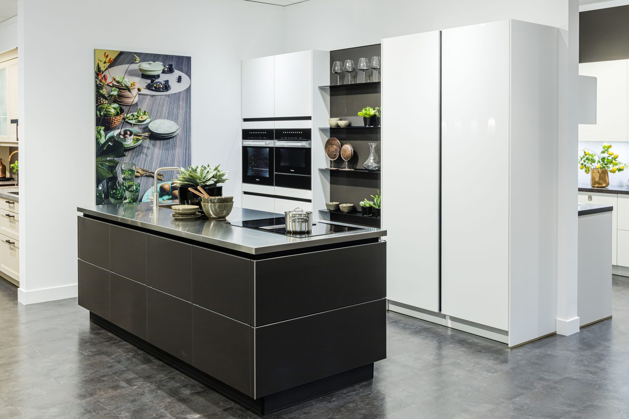 Het lavazwarte kookeiland staat in mooi contrast met de witte kastenwand