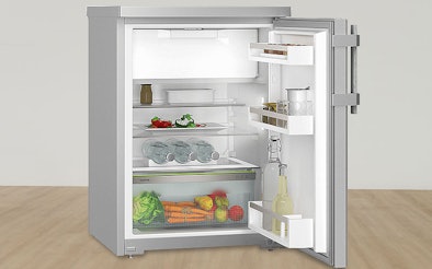 Binnenkant van een tafelmodel koelkast met groentelade, flessenrek en verstelbare glasplateaus.