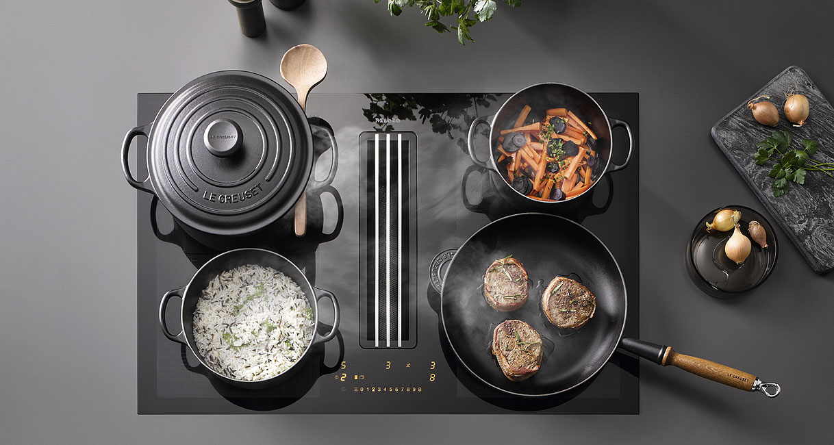 Miele inductiekookplaat met 2 PowerFlex XL-zones met meerdere pannen en een braadslede op het kookoppervlak