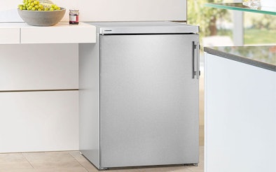 Vrijstaande tafelmodel koelkast van roestvrij staal geplaatst in moderne keuken, goed geventileerd naast werkblad.