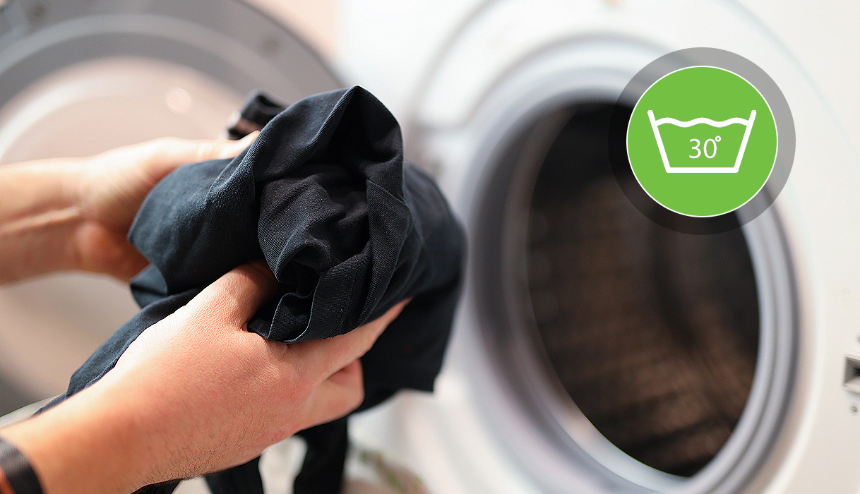 Zwarte kleding wordt met de hand in de wasmachine geplaatst op 30 graden