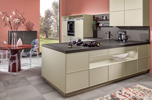 Zandkleurige moderne keuken met kookeiland, donker antraciet werkblad en terracotta wand volgens de 60-30-10 kleurregel.