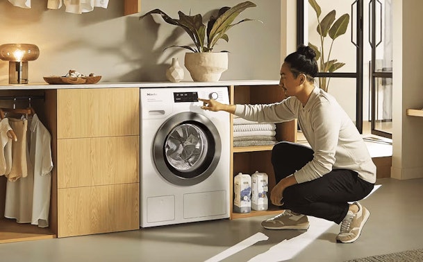 Man stelt een Miele wasmachine 9 kg in met TwinDos en PowerWash in moderne wasruimte.