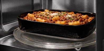 Grote ovenschaal pasta bolognese in magnetron bereid op 900 watt of hoger voor intensief koken van grote porties