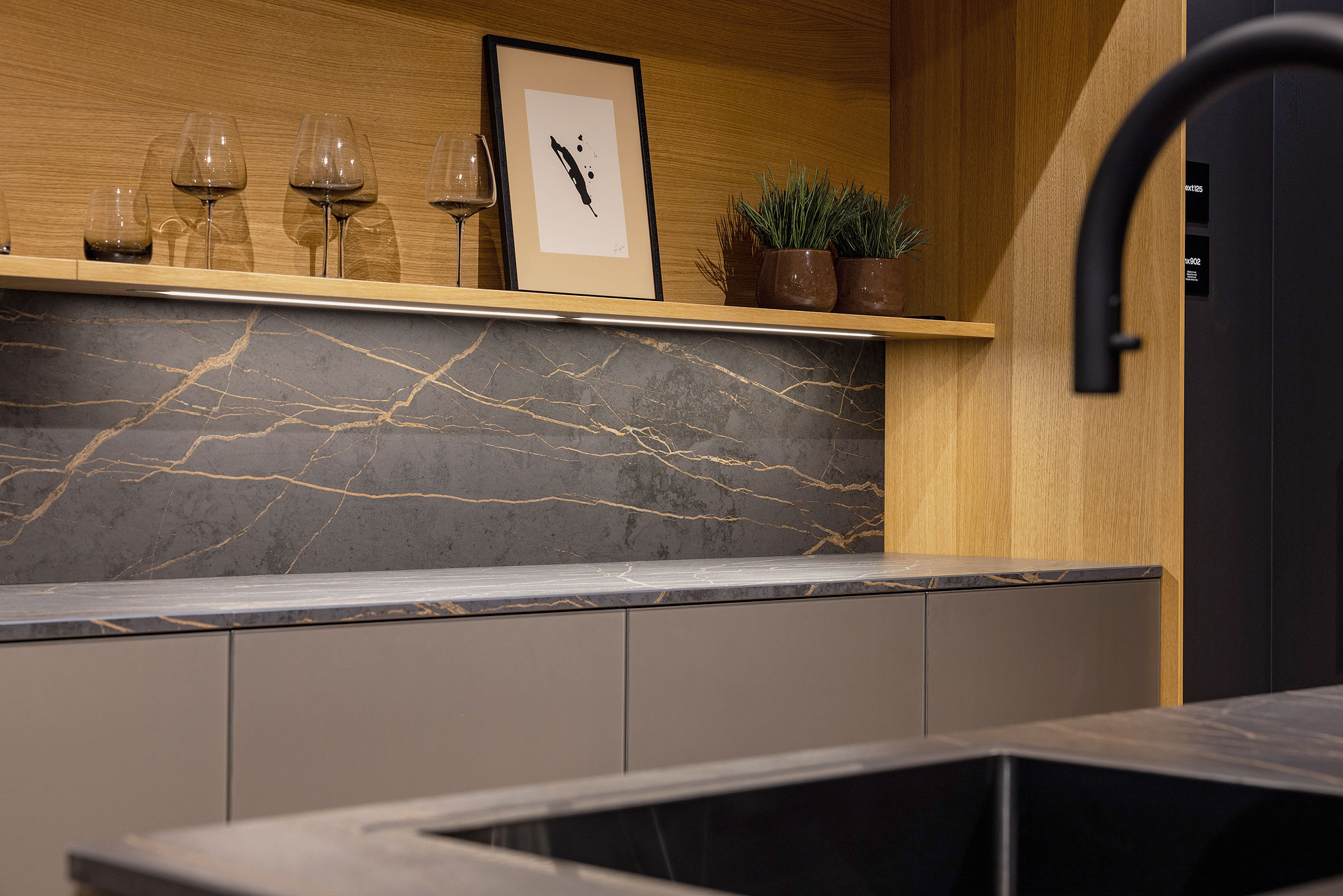 Koel, elegant glas, harde steen en warm hout komen in deze keuken samen als een eigenzinnig samengestelde outfit.