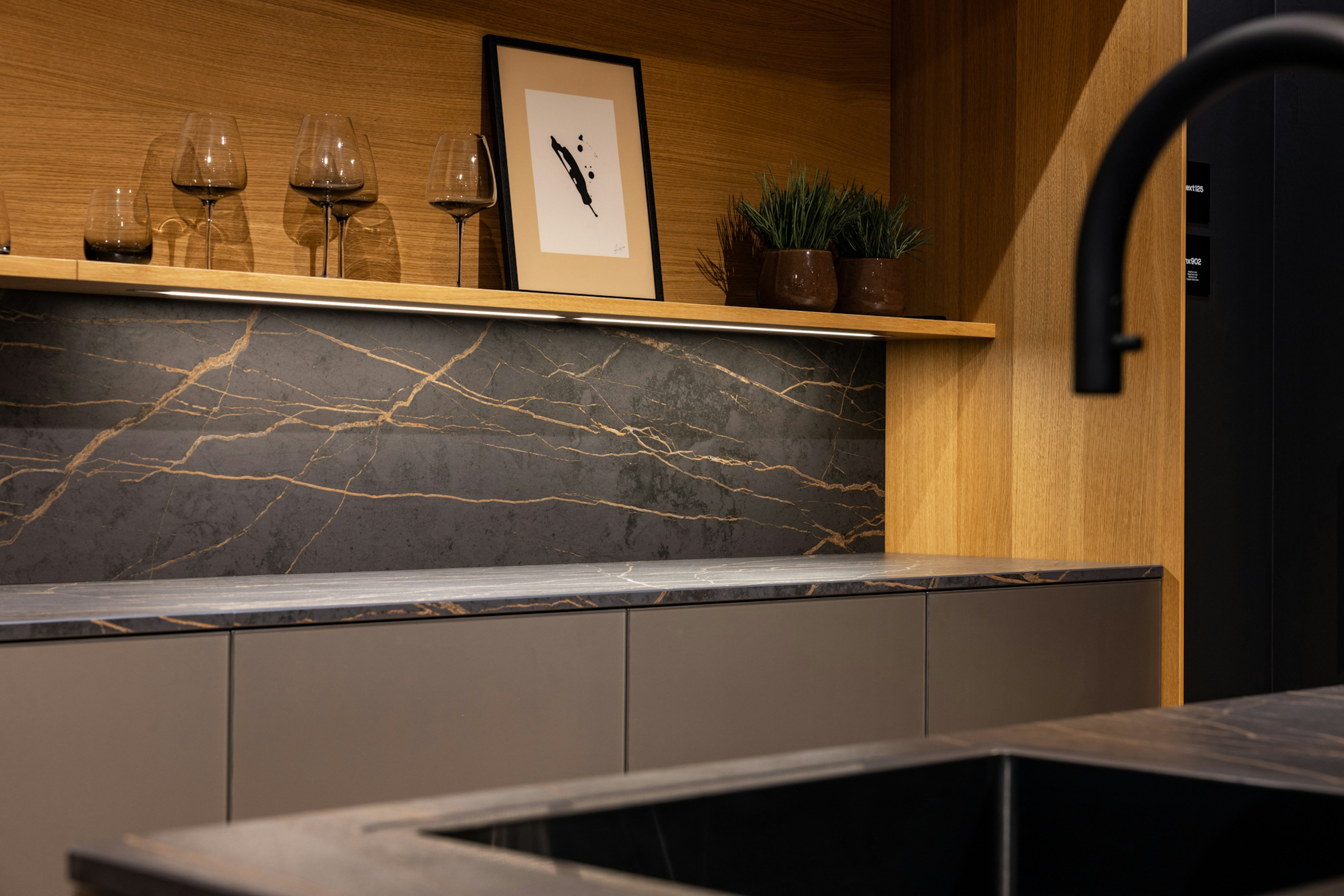 Koel, elegant glas, harde steen en warm hout komen in deze keuken samen als een eigenzinnig samengestelde outfit.
