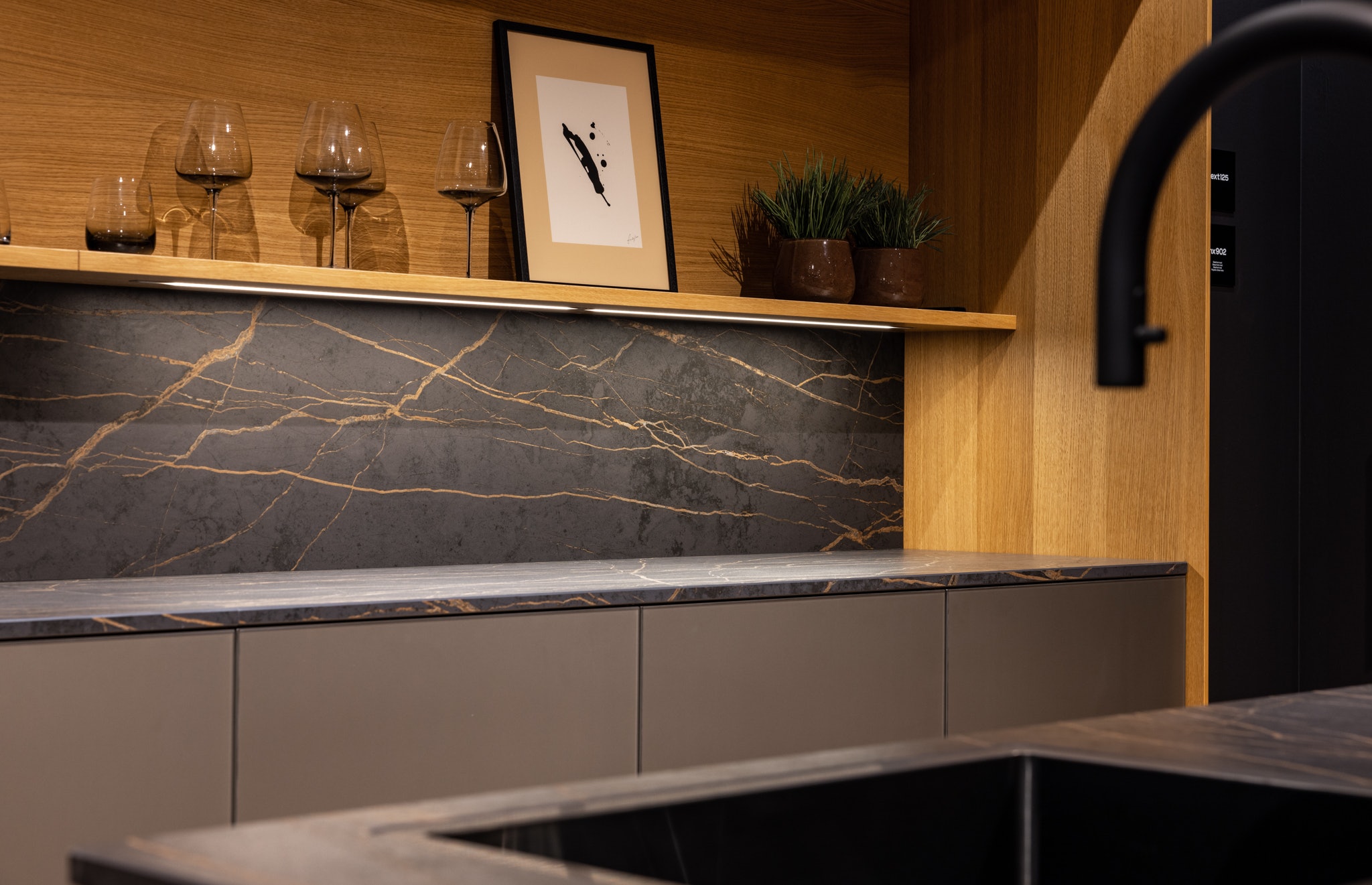 Koel, elegant glas, harde steen en warm hout komen in deze keuken samen als een eigenzinnig samengestelde outfit.