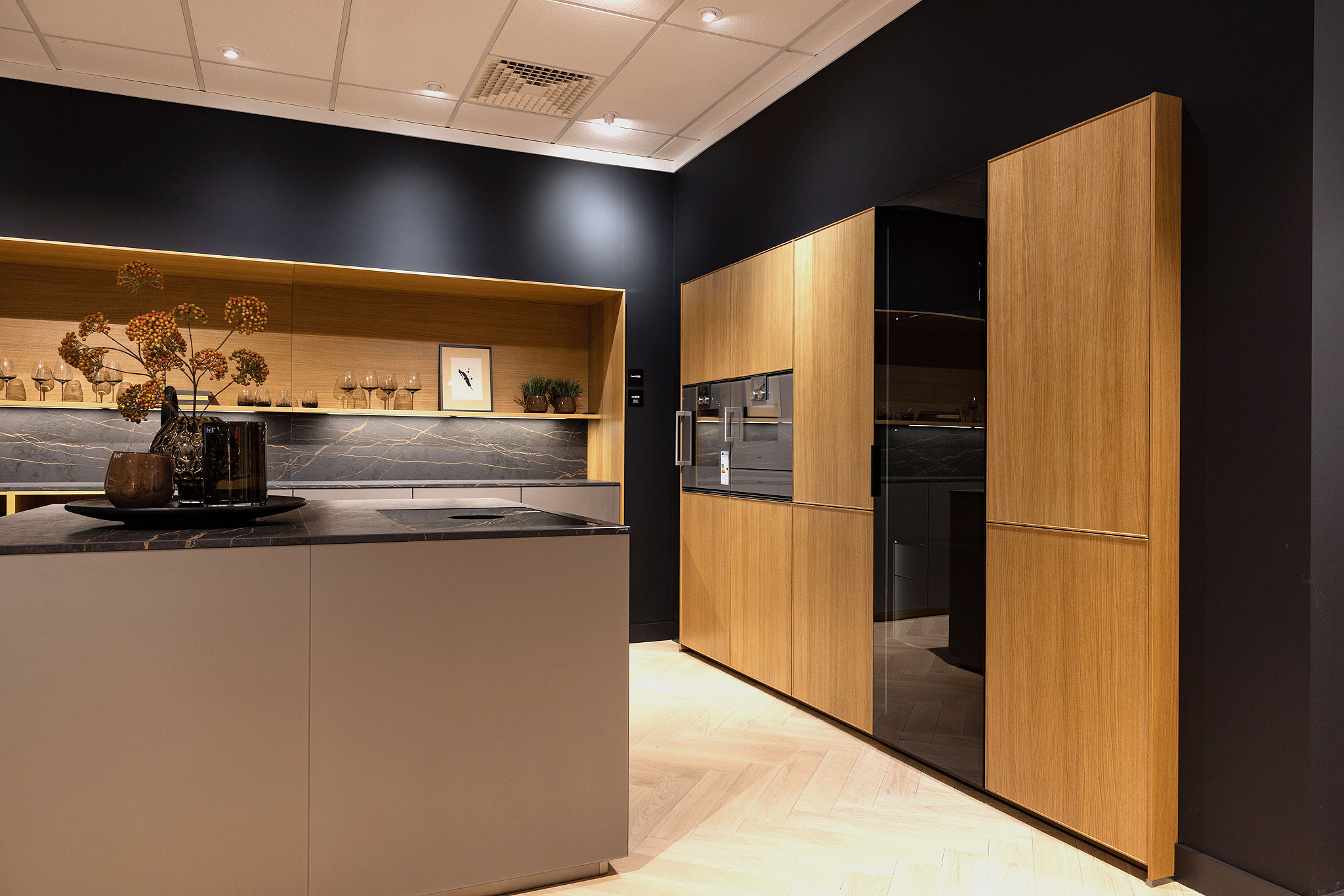 In de houten kastenwand bevindt zicht een verlichte zwart glazen servieskast.