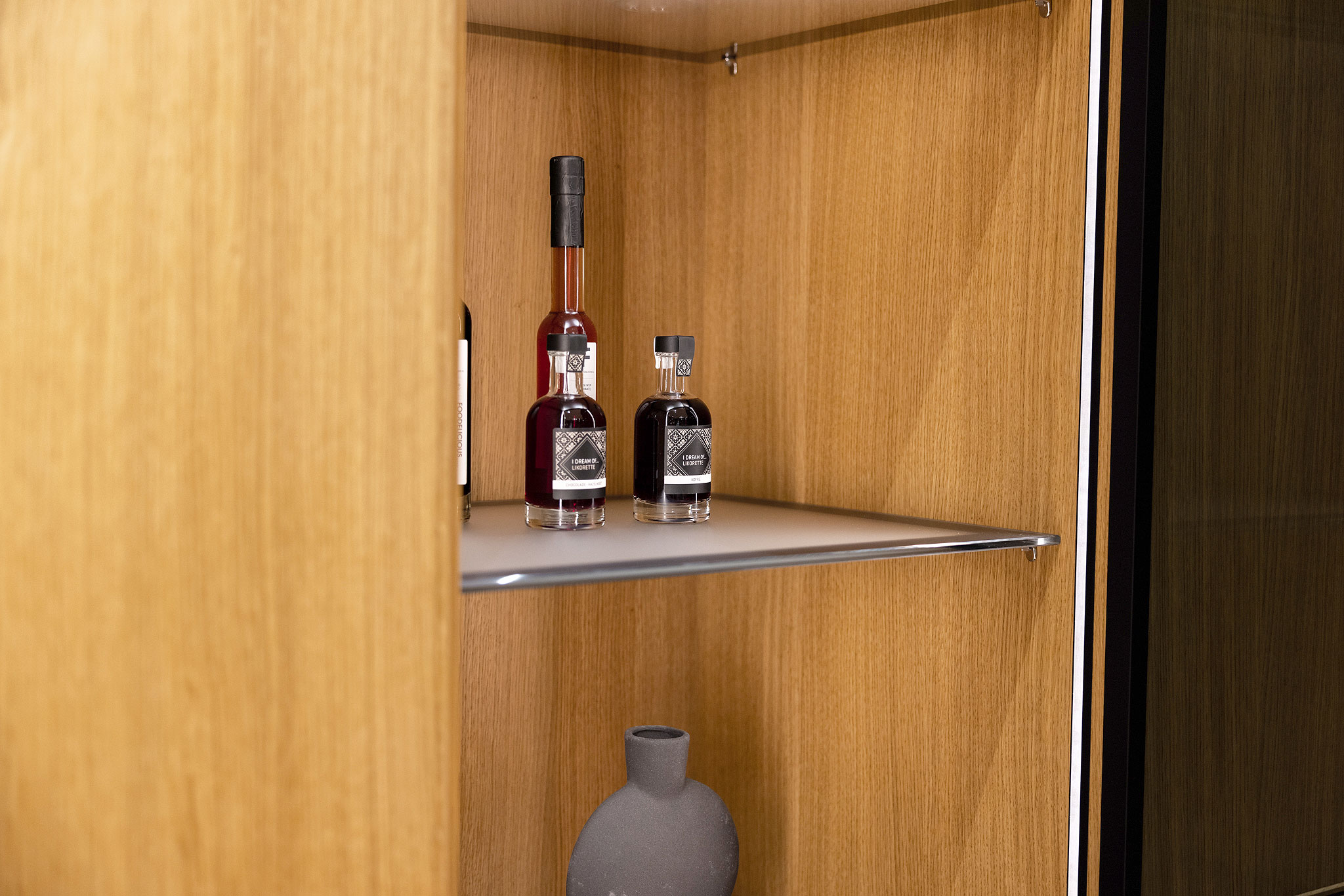 De gesatineerde glazen legplanken met onyxzwarte passe-partouts.