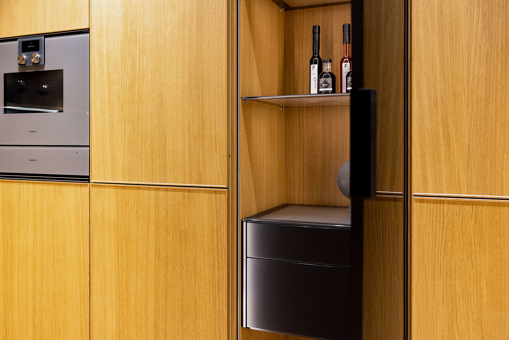 De vitrinekast is een echte blikvanger in de met houten design kaderdeurtjes voorziene kastenwand.