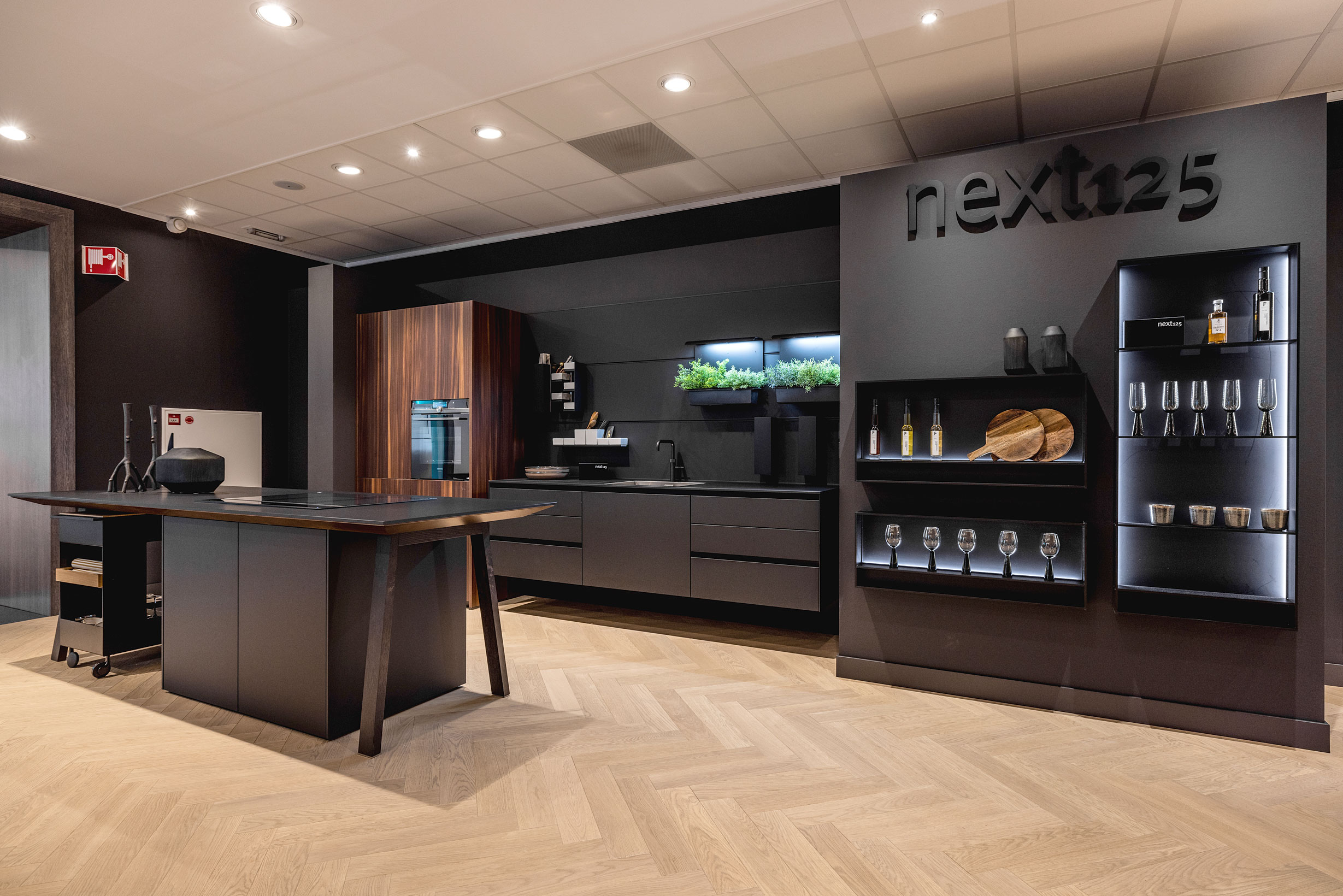 Deze buitengewone keukenopstelling maakt indruk door een centraal geplaatste kooktafel en wandhangend spoelgedeelte.