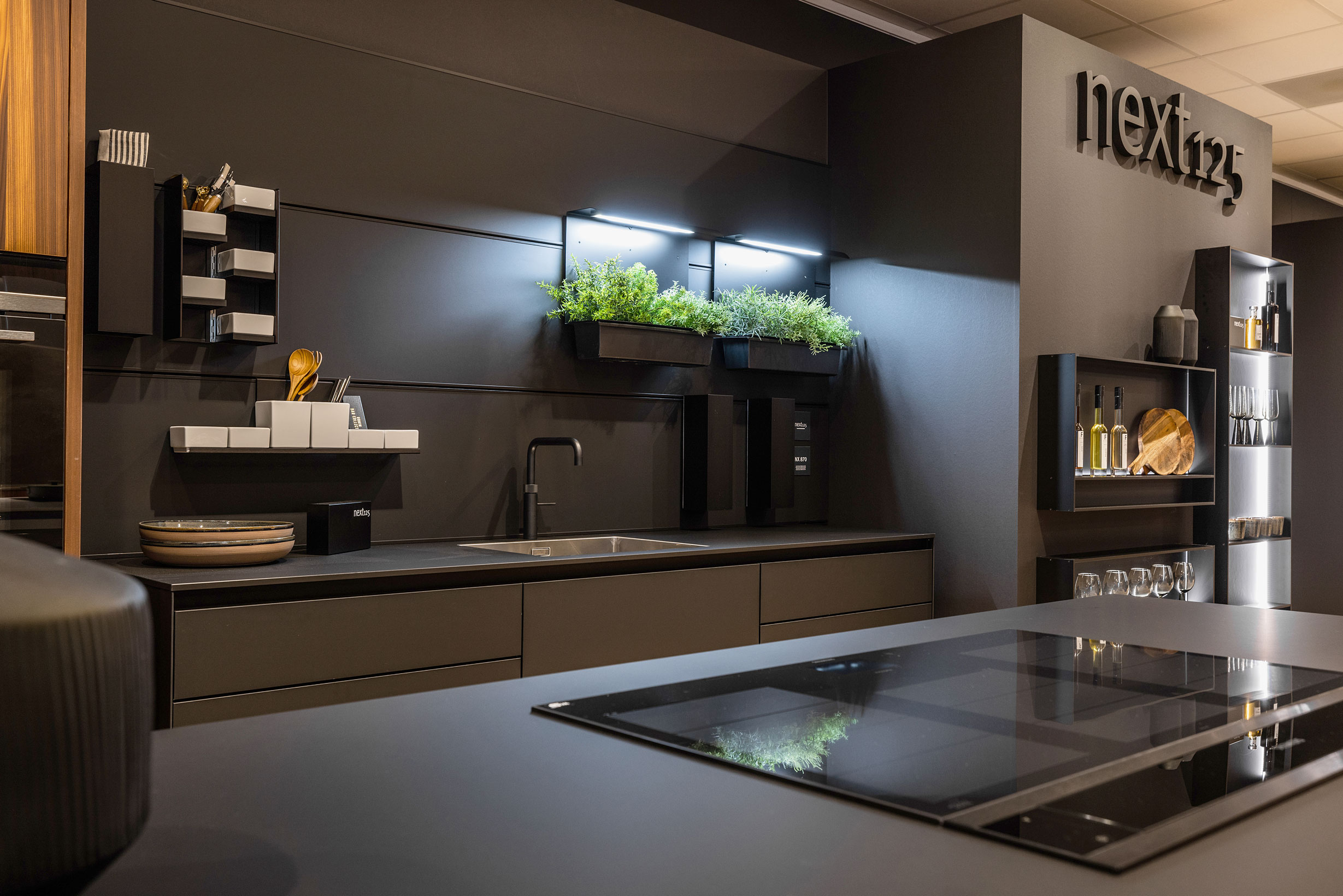 De keukenfronten, werkbladen en verlichte Framewall zijn allen uitgevoerd in onyxzwart Fenix.