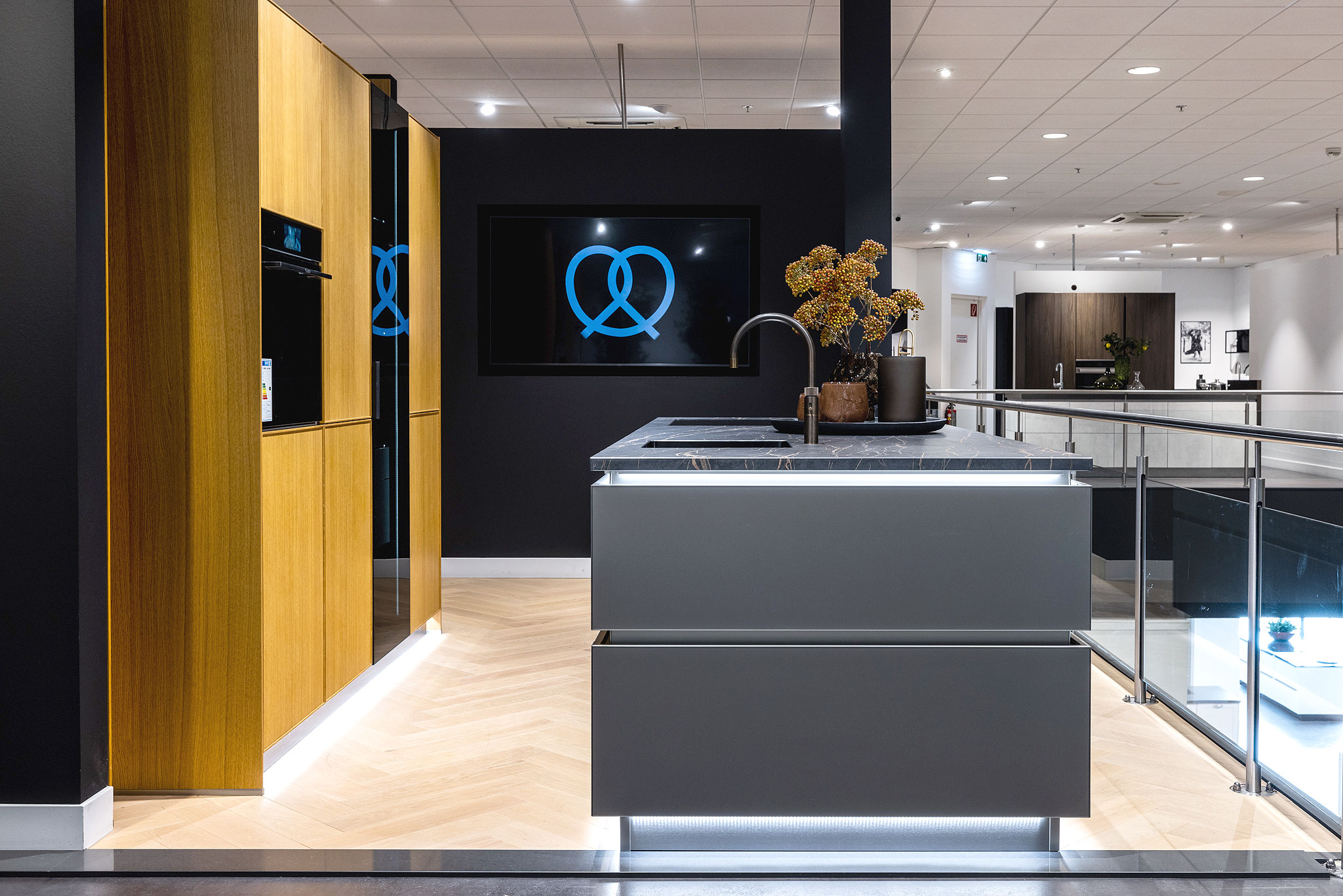 De combinatie van de verticale structuur van het hout met de verlichte greeplijst benadrukt de belijning in de keuken extra.