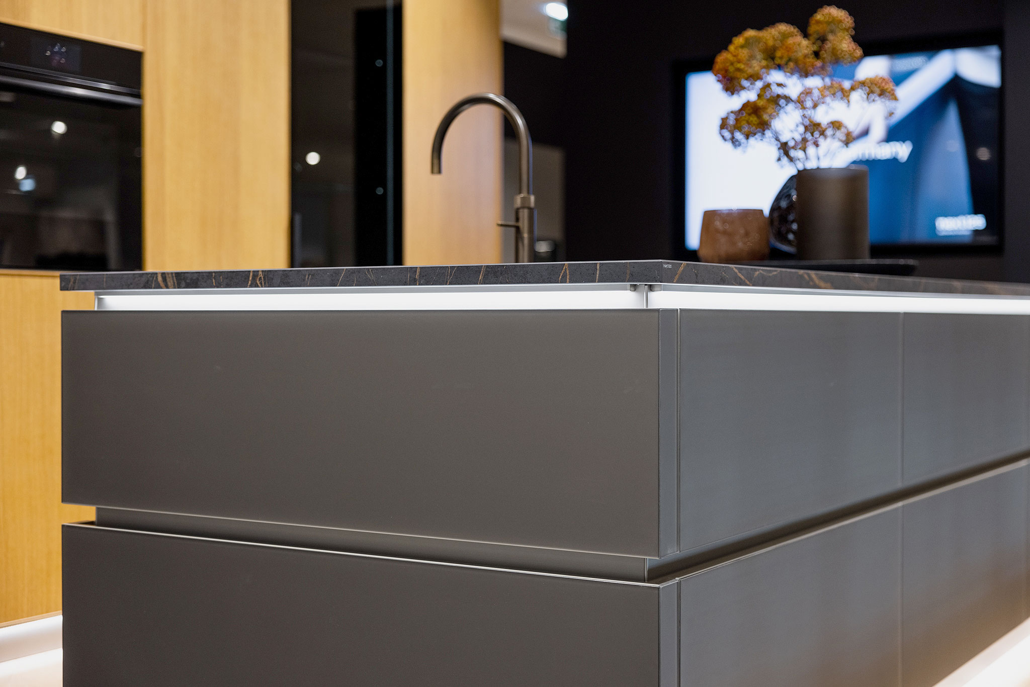 Het Dekton werkblad lijkt door de verlichte greep lijsten boven het eiland te zweven.