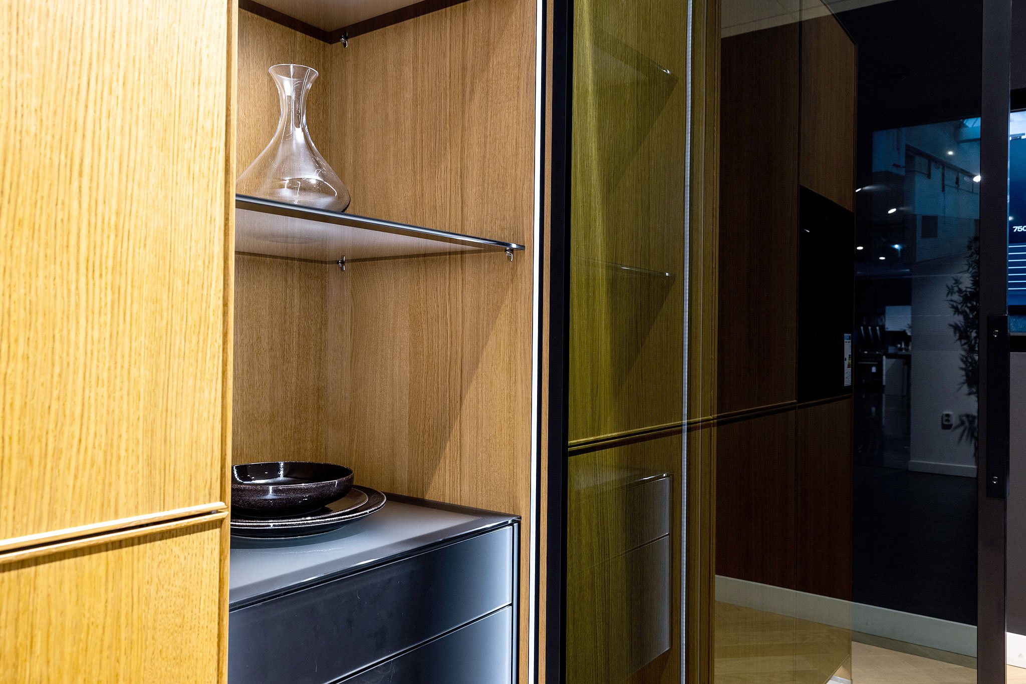 De vitrinekast is een echte blikvanger in de met houten design kaderdeurtjes voorziene kastenwand.