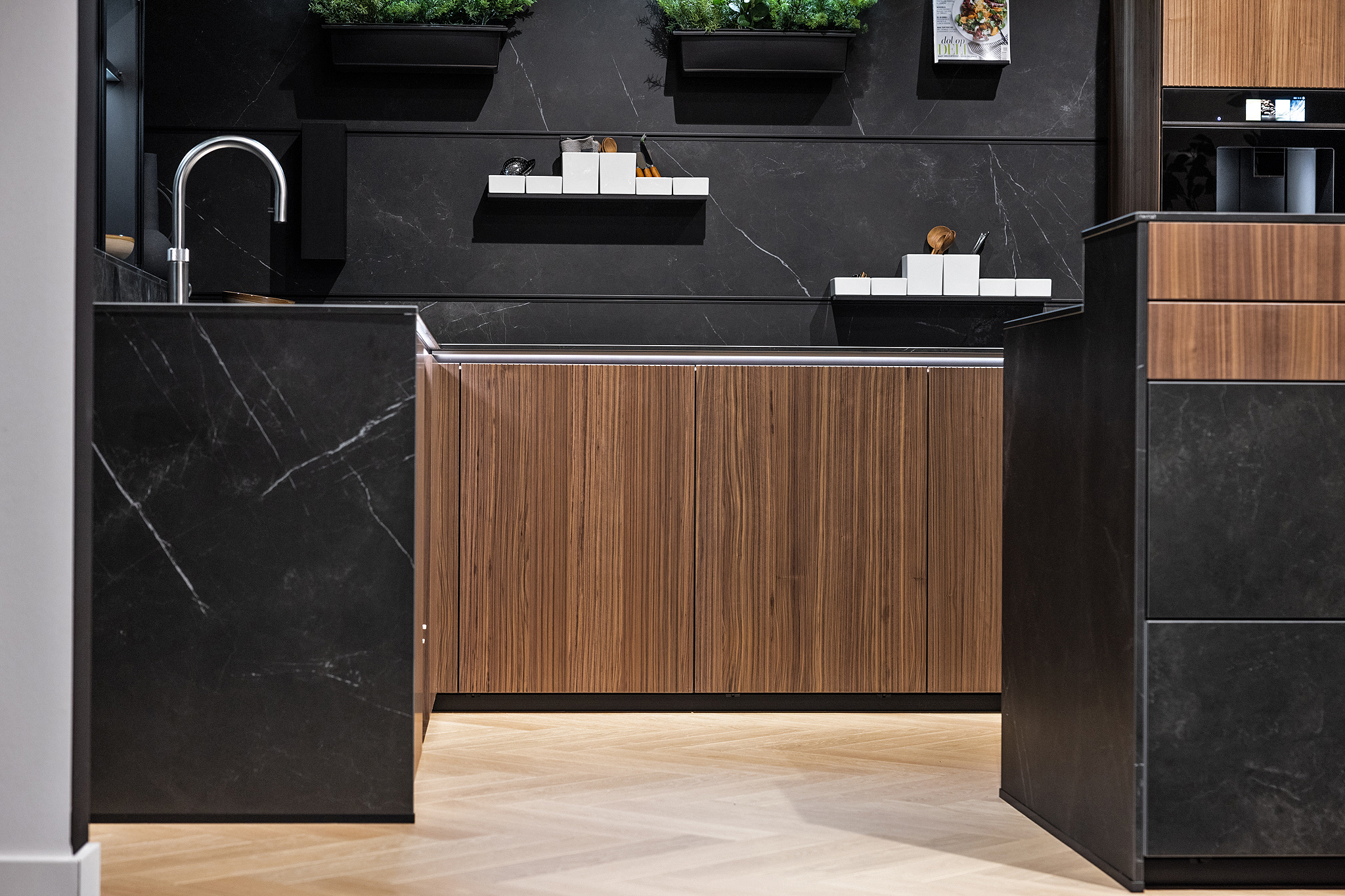 De notenhouten fronten met verticale lamellen, geven de keuken een warme en sfeervolle uitstraling.