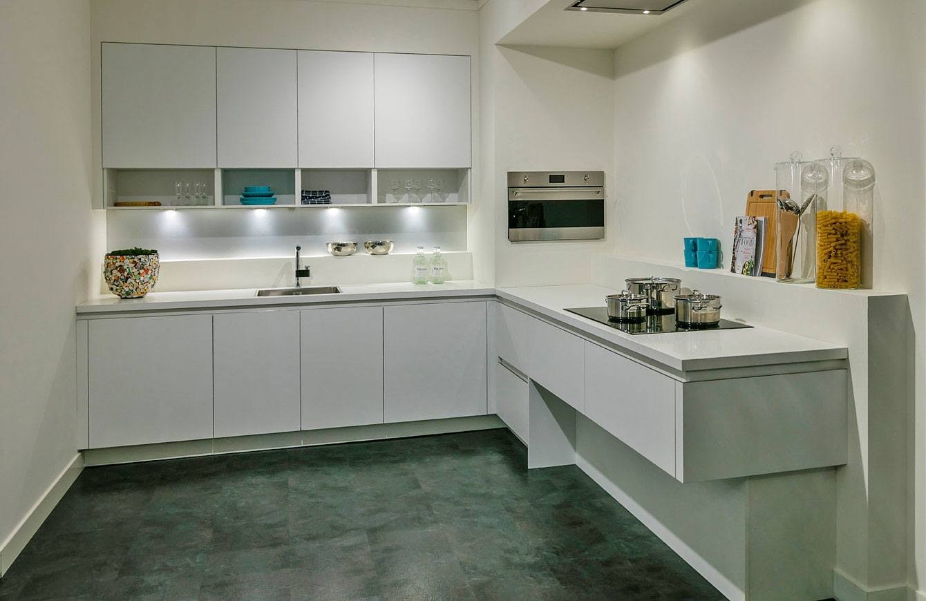 Deze moderne greeploze witte keuken is voorzien van een composiet werkblad.