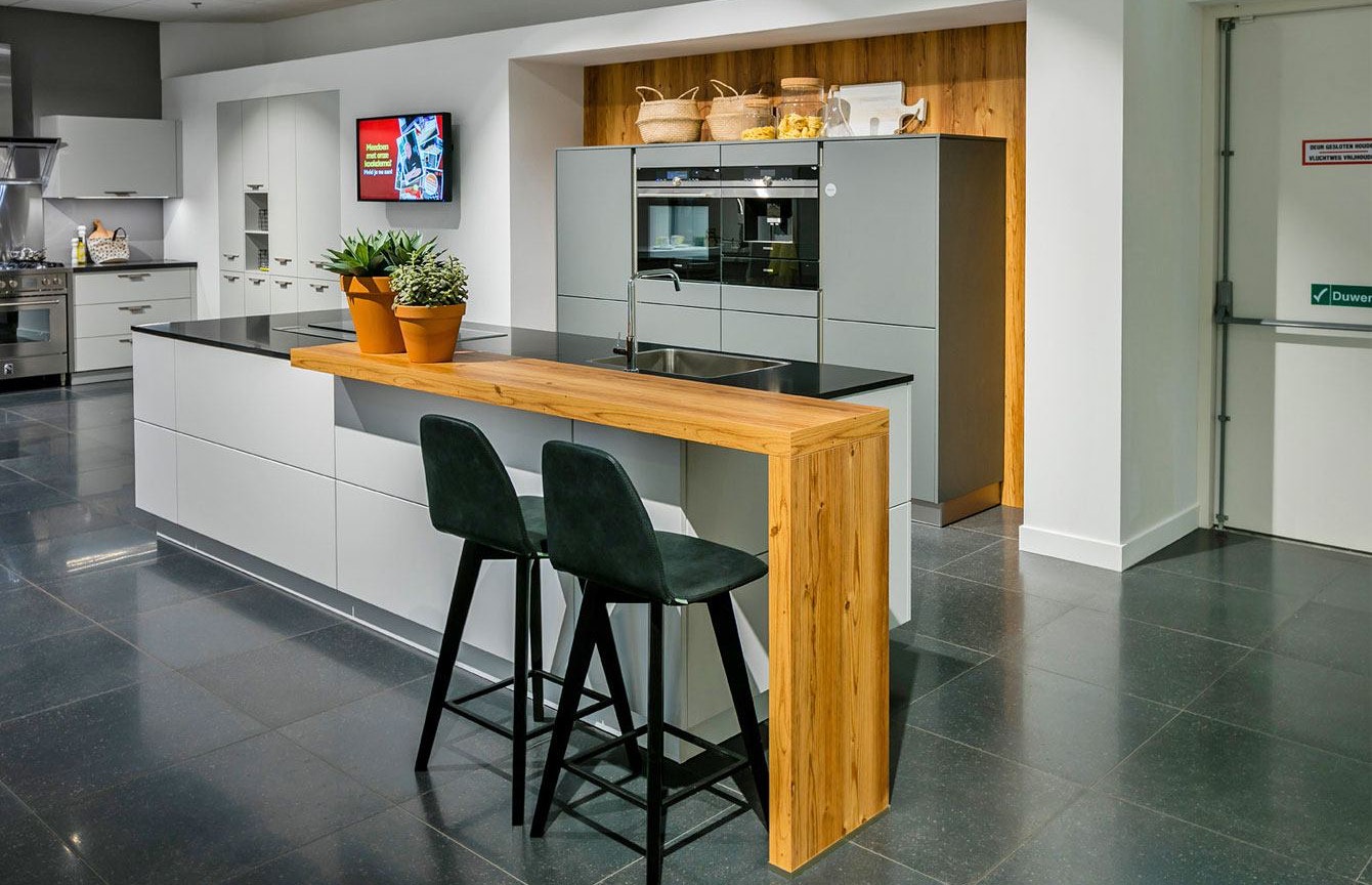 Moderne keuken in twee kleuren met houten bar.