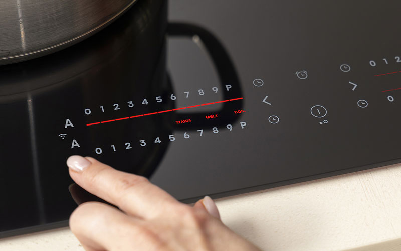 Pelgrim inductiekookplaat met LightOnly sliderbediening waarbij een gebruiker de kookstand via verlichte touchslider op het glasoppervlak instelt