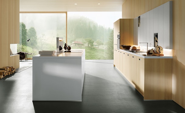 Lichte Scandinavische keuken met wit kookeiland, houten fronten en grote ramen met uitzicht op de natuur