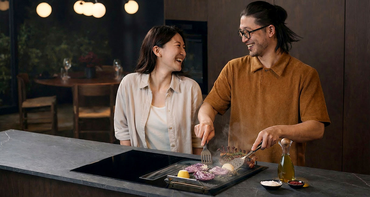Stel kookt vrolijk samen op een kookplaat met geïntegreerde afzuiging zonder lawaaiige traditionele afzuigkap boven het hoofd