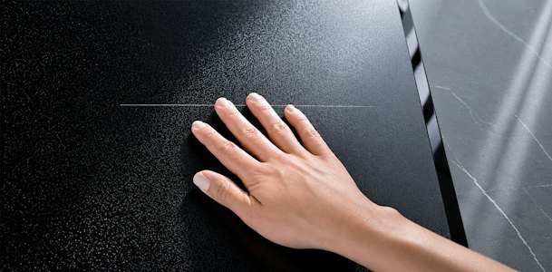 Hand strijkt over het matte glas van een AEG kookplaat in het werkblad