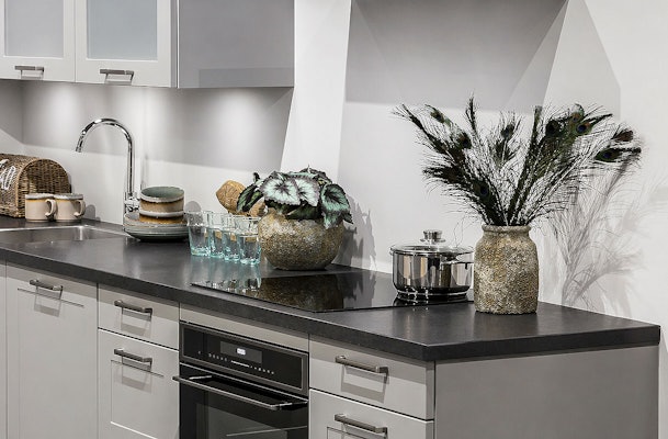 Rechte keuken met inbouwoven, kookplaat, spoelbak en decoratie met pauwenveren en plant