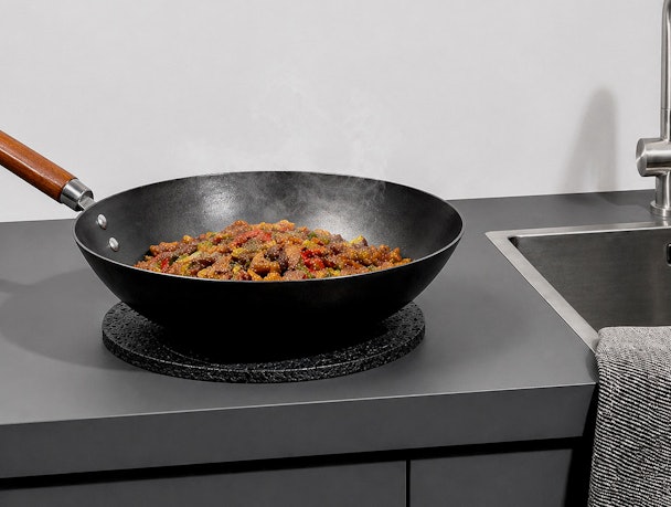 Greengridz keukenblad met hete wokpan op onderzetter naast een spoelbak in moderne keuken