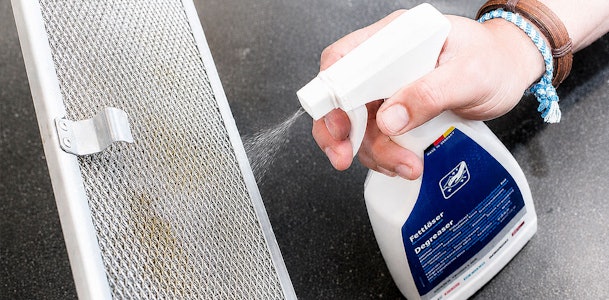 Ontvetter wordt op het vetfilter van de afzuigkap gespoten tegen aangekoekt vet