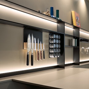 Taupekleurige glazen achterwand met frame nissysteem.