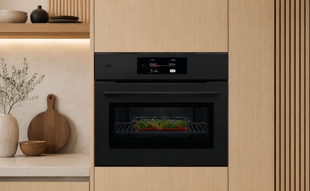 AEG combi oven magnetron ingebouwd in een lichte Japandi keuken met zwarte oven, display en ovenschotel.