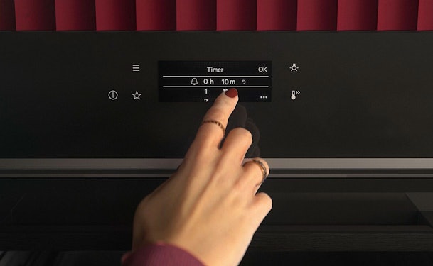 Bediening van een AEG combimagnetron met touchscreen waarop de kookwekker en timer worden ingesteld.