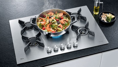 Pan met pasta en garnalen op de brandende wokbrander van een AEG gaskookplaat