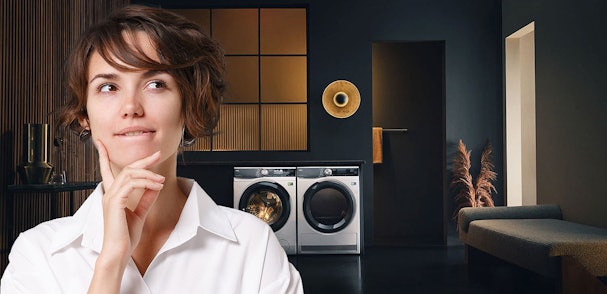 Vrouw denkt na bij wasmachine en droger in moderne wasruimte