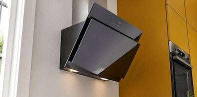Schuine wandschouwkap met verlichting in keuken naast inbouwoven