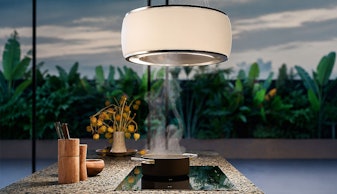 Falmec design afzuigkap met geïntegreerde verlichting boven een kookeiland met dampende pan