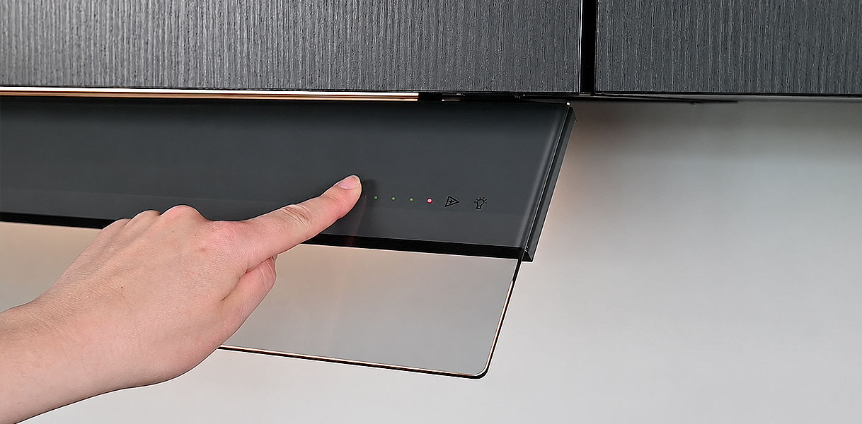 Vinger bedient de touch-toetsen met indicatieledjes op een Novy afzuigkap om de filterindicatie te resetten