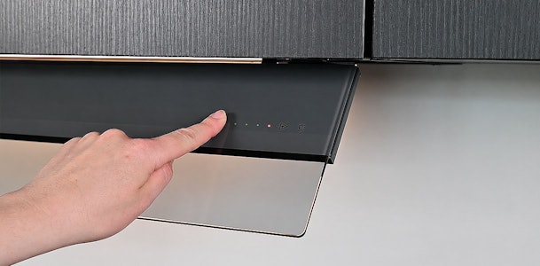 Vinger bedient de touch-toetsen met indicatieledjes op een Novy afzuigkap om de filterindicatie te resetten