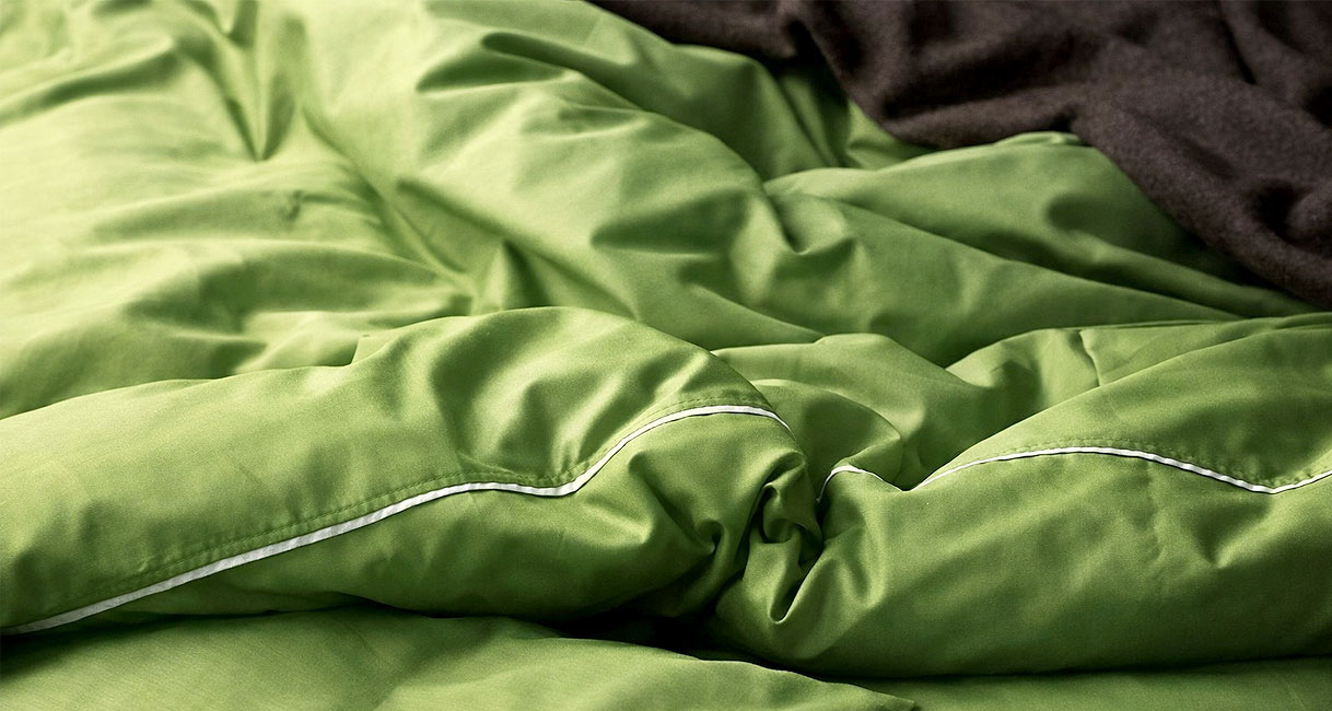 Groen dekbed met witte bies in close up als voorbeeld van allergie modus wasprogramma