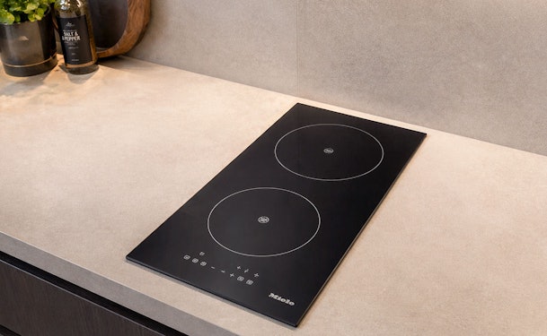 Compacte inductiekookplaat met twee zones in werkblad naast peper en zoutmolen