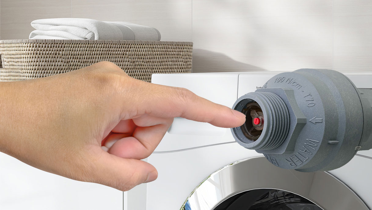 Vinger drukt rood pinnetje in Aquastop-connector van wasmachine waterslang om te resetten