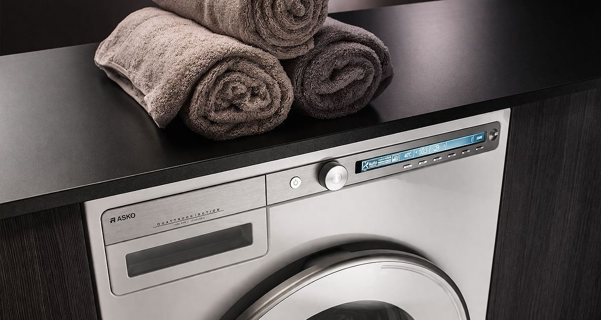 ASKO Logic warmtepompdroger met minimalistisch design en digitaal display naast opgerolde handdoeken