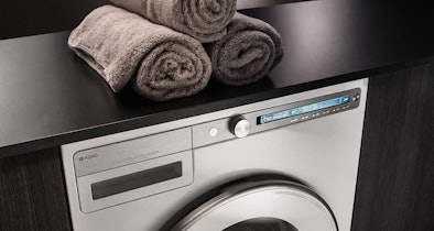ASKO Logic warmtepompdroger met minimalistisch design en digitaal display naast opgerolde handdoeken