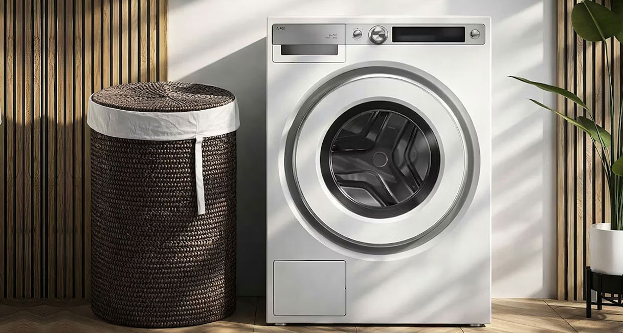 ASKO Style droger in wit met ronde trommel in moderne wasruimte met rieten wasmand en houten wandpanelen