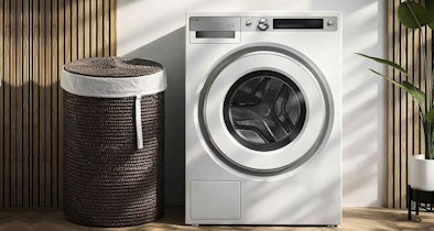 ASKO Style droger in wit met ronde trommel in moderne wasruimte met rieten wasmand en houten wandpanelen