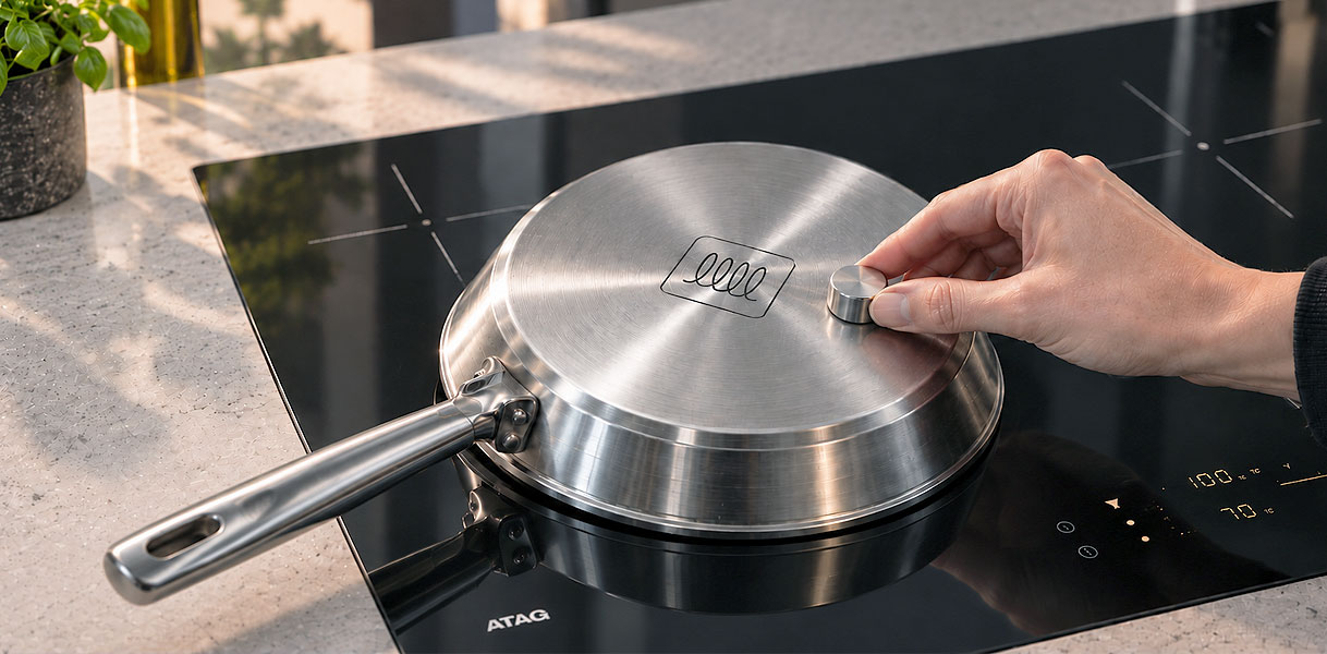 Hand houdt een magneet tegen de bodem van een pan op een ATAG kookplaat