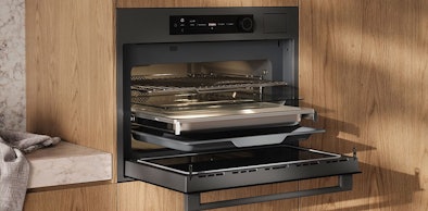 ATAG magnetron 8-serie met open ovendeur ingebouwd in een moderne houten keuken