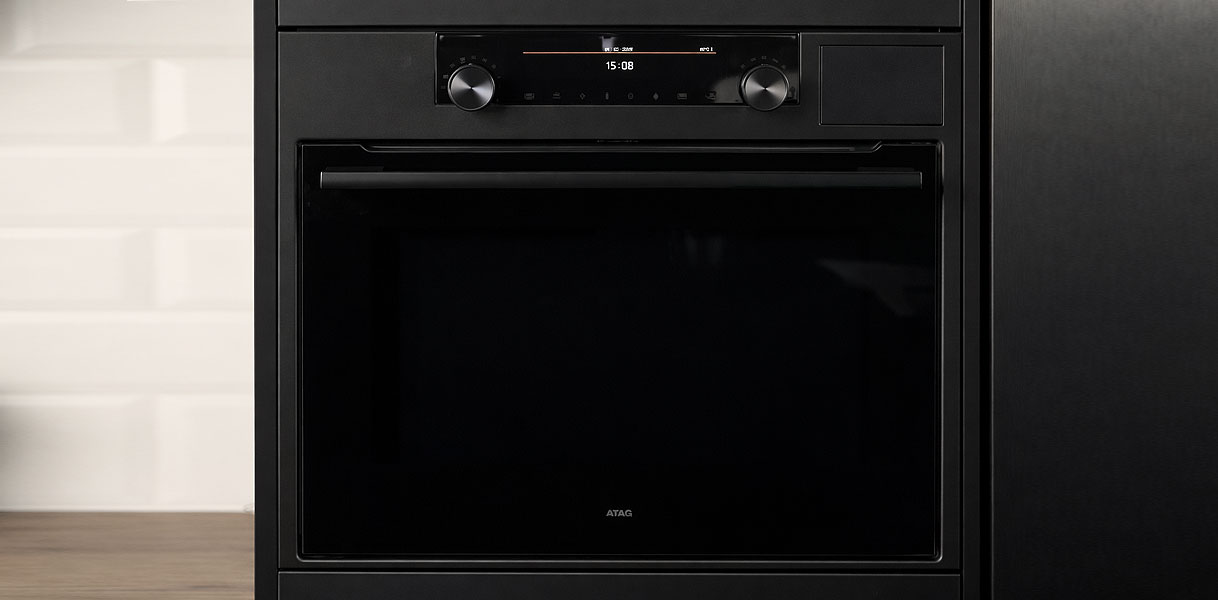 ATAG magnetron MAGNA in Soft Black met metalen draaiknoppen en touch control bediening ingebouwd in lichte keuken