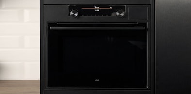 ATAG magnetron MAGNA in Soft Black met metalen draaiknoppen en touch control bediening ingebouwd in lichte keuken